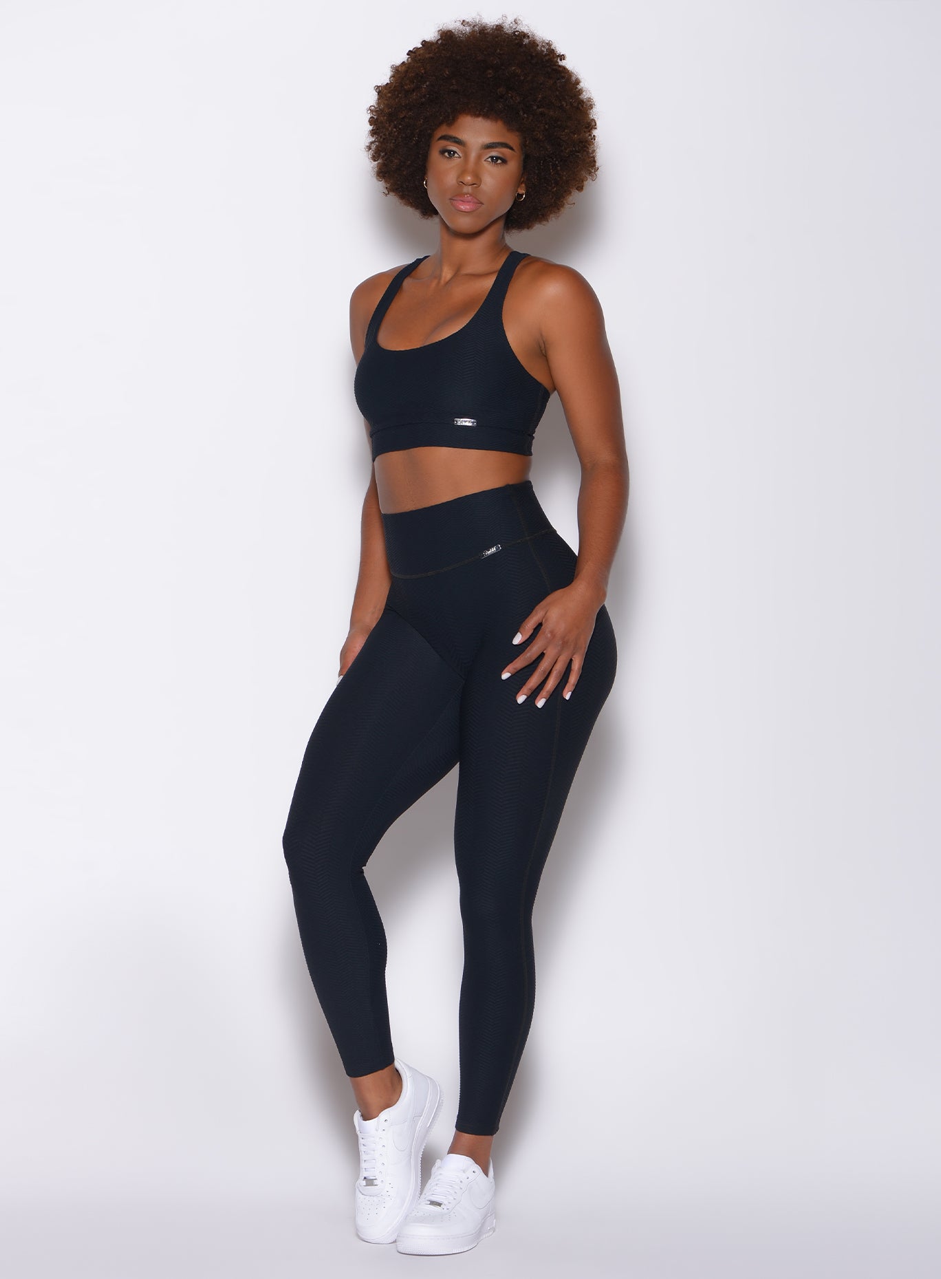 Left side profile view of a model wearing our Chevron Leggings in jet black color and matching bra